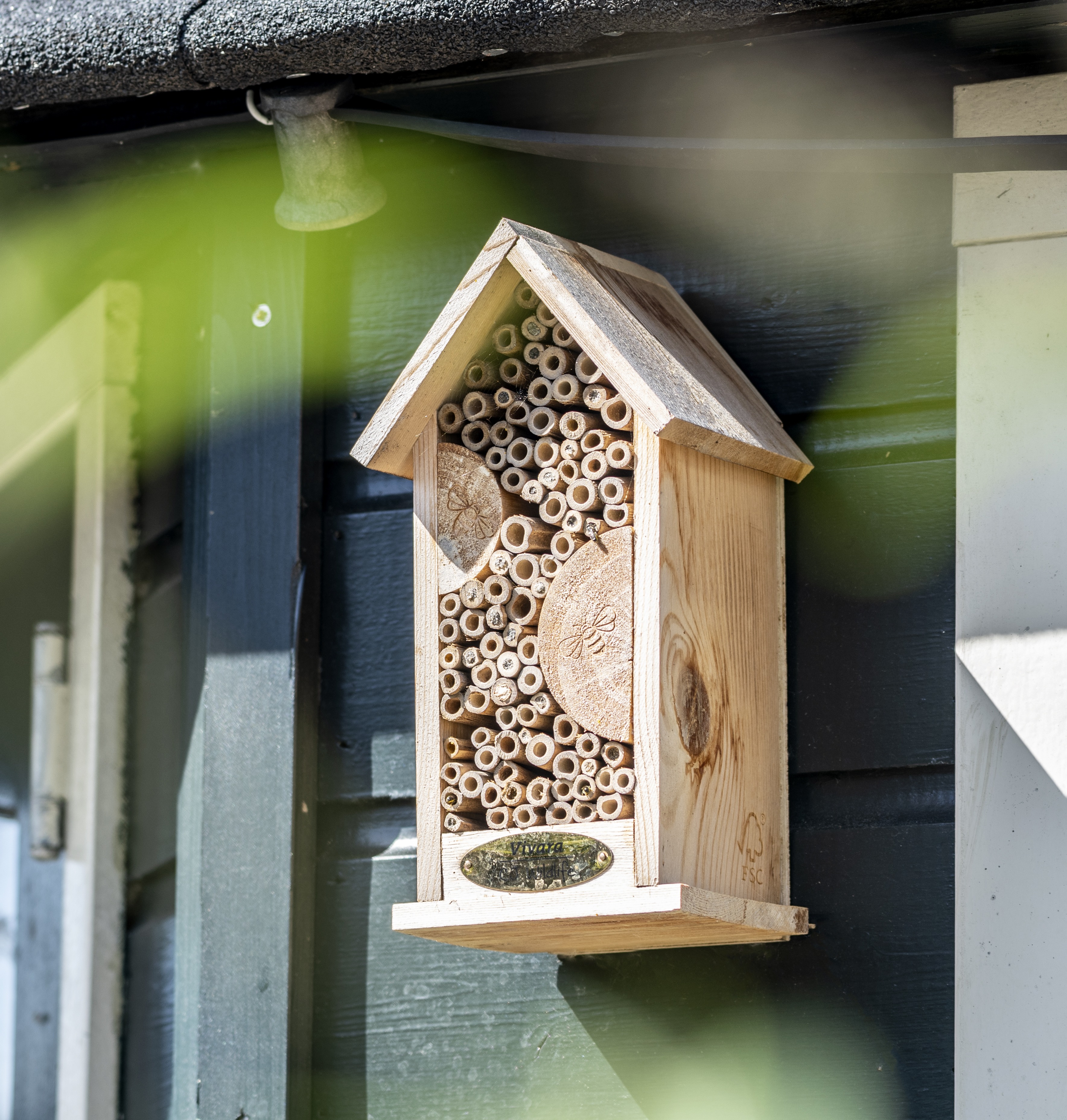 Foto van een bijenhotel van hout aan een huis